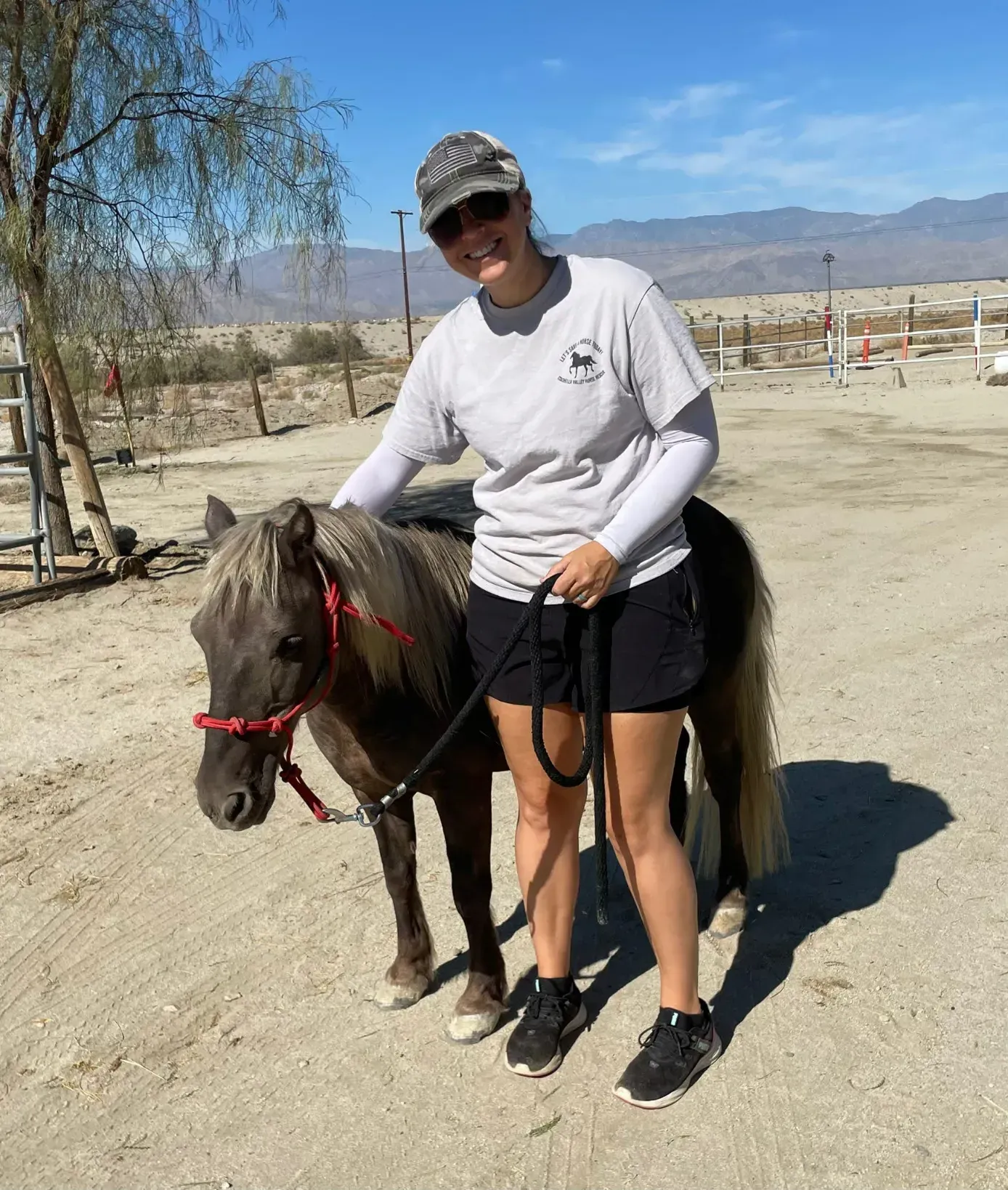 A volunteer leading a miniature horse at the ranch