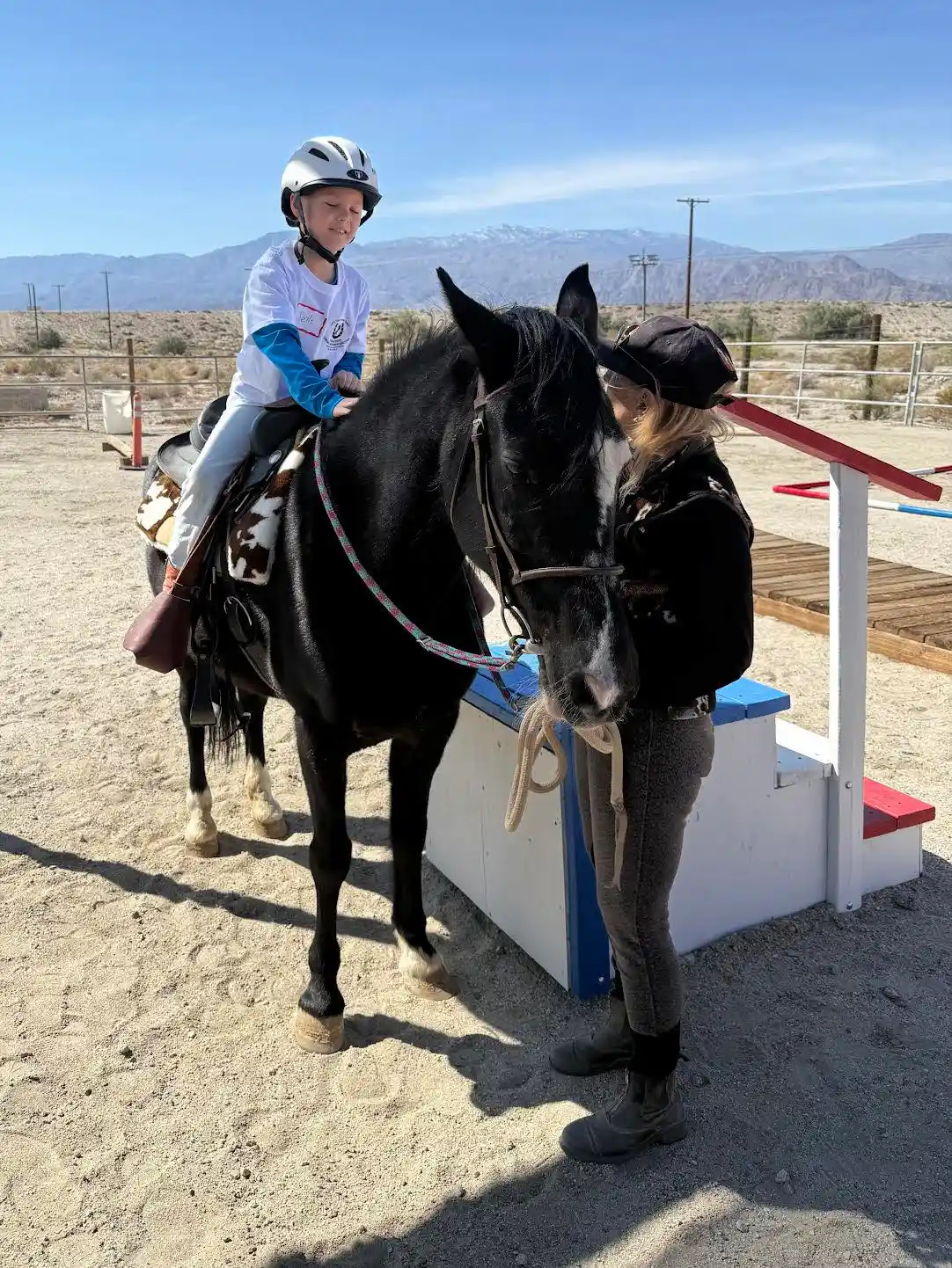 A child riding a rescue horse with a volunteer leading